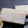 Raw frozen dory steak displayed on a black marble plate