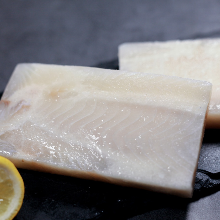 Raw frozen dory steak displayed on a black marble plate